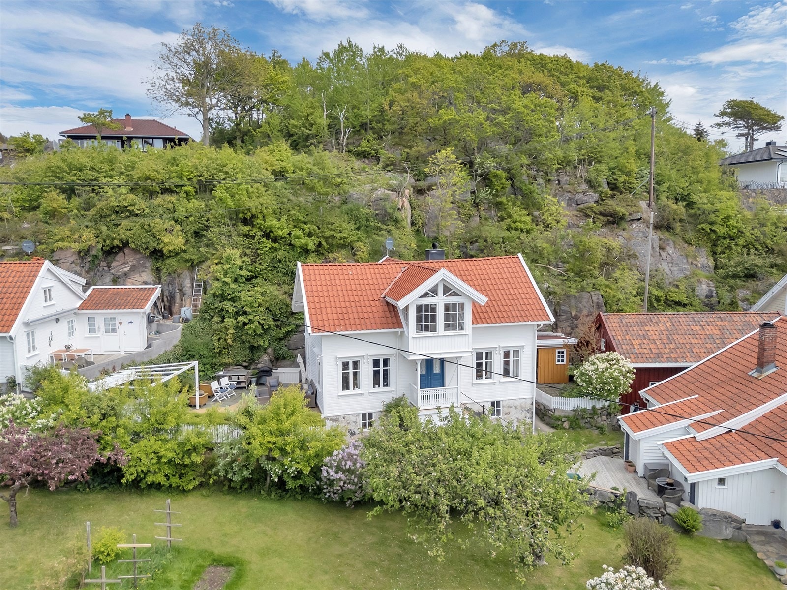 Eiendommen ligger i skrånet terreng, omkranset av hage og natur. Galleribilde