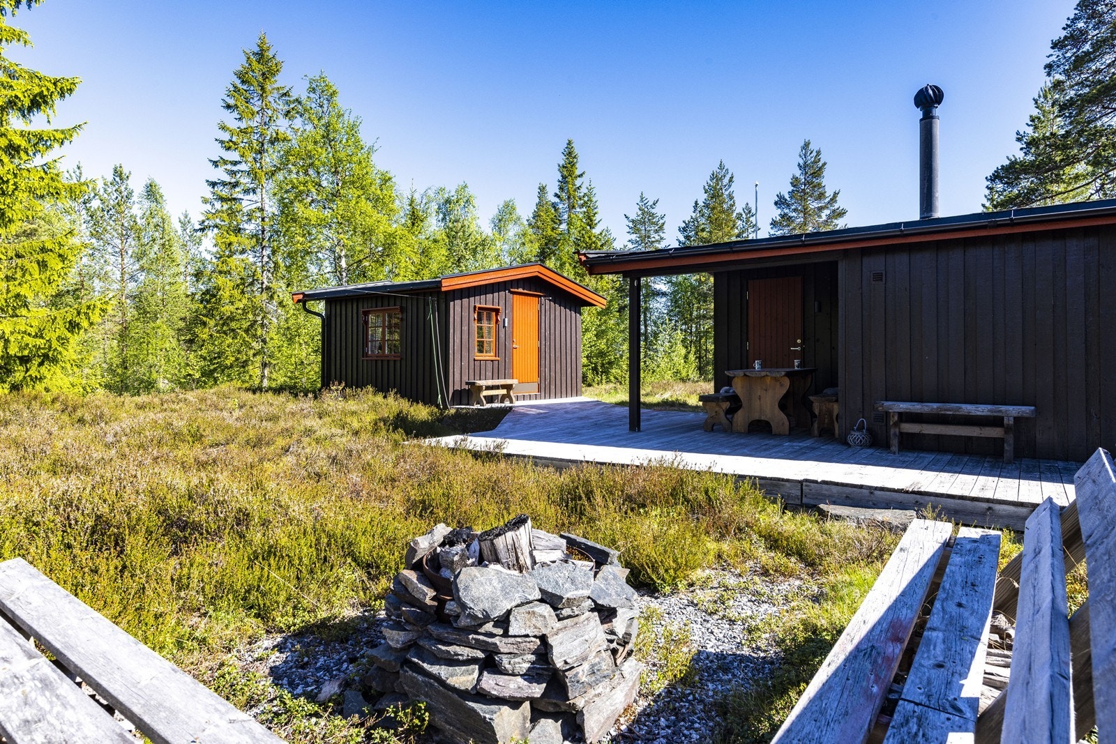 En platting på 40 m² binder sammen bygningene og gir rikelig med plass for uteliv på den flate naturtomten. Galleribilde