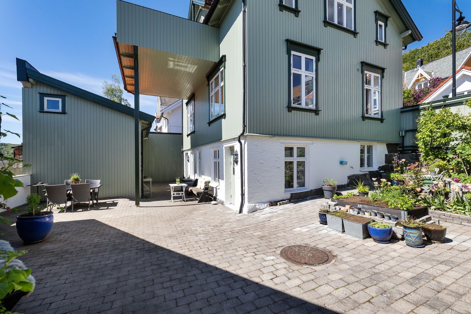 Gårdsplassen er inngjerdet med beplantning og belegningsstein. Galleribilde