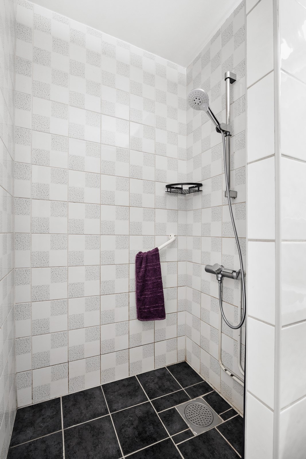 Badet har dusjnisje, toalett, servantskap og speil. Galleribilde