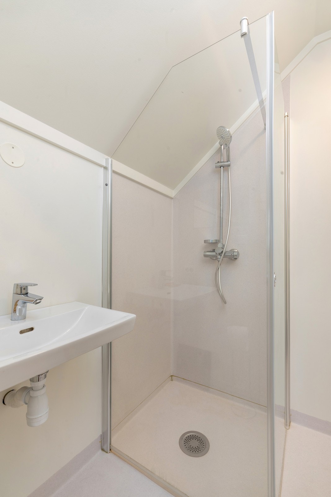 Bad med belegg på gulv. Badet har dusjhjørne, servant og toalett. Galleribilde