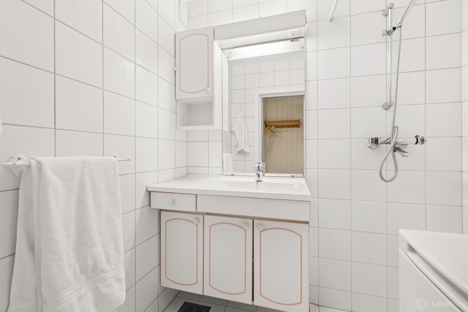 Lyst bad med varmekabler i gulv, dusjløsning og opplegg for vaskemaskin. Galleribilde