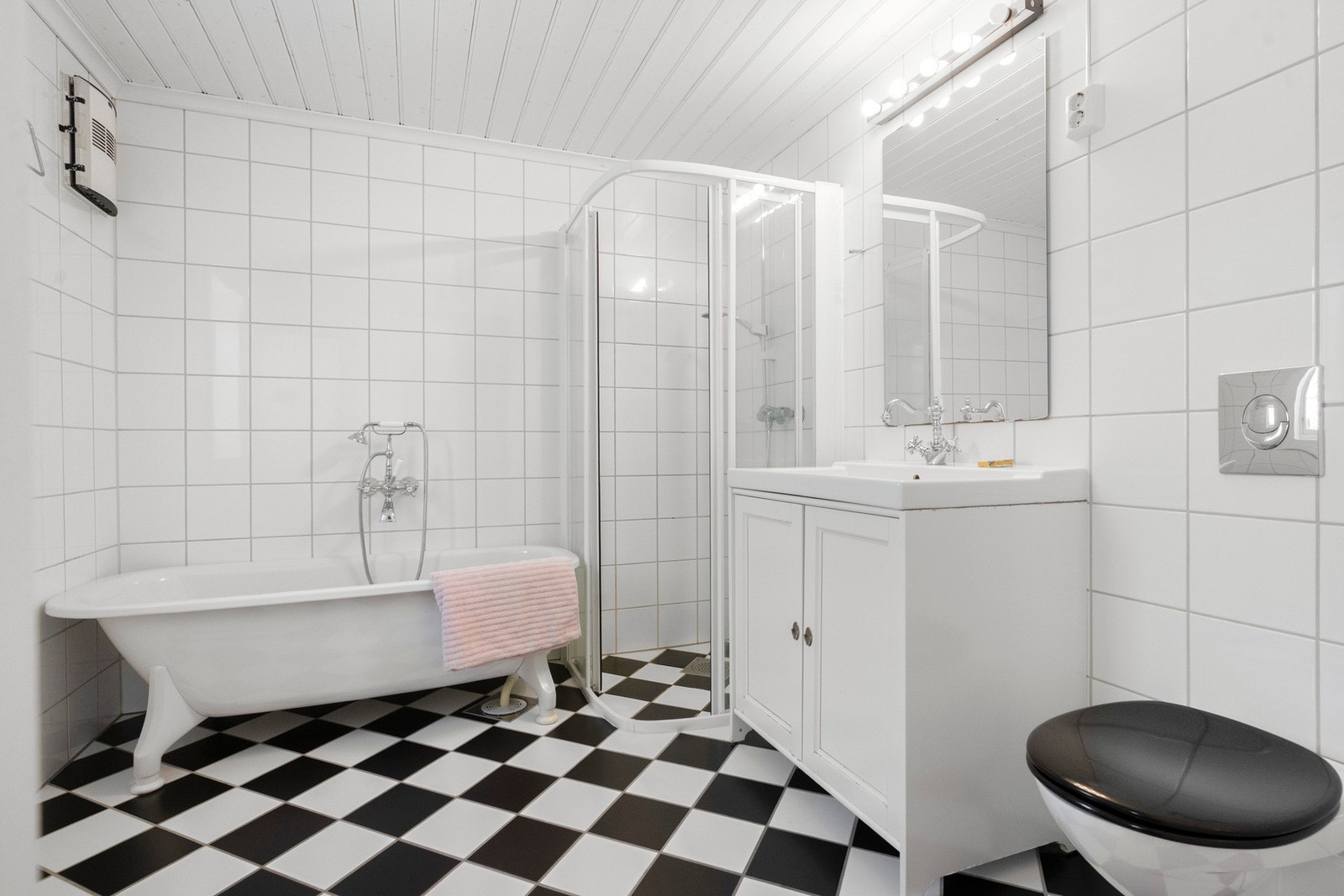 Badet er innredet med badekar, dusjhjørne, toalett og servangt med skap. Galleribilde