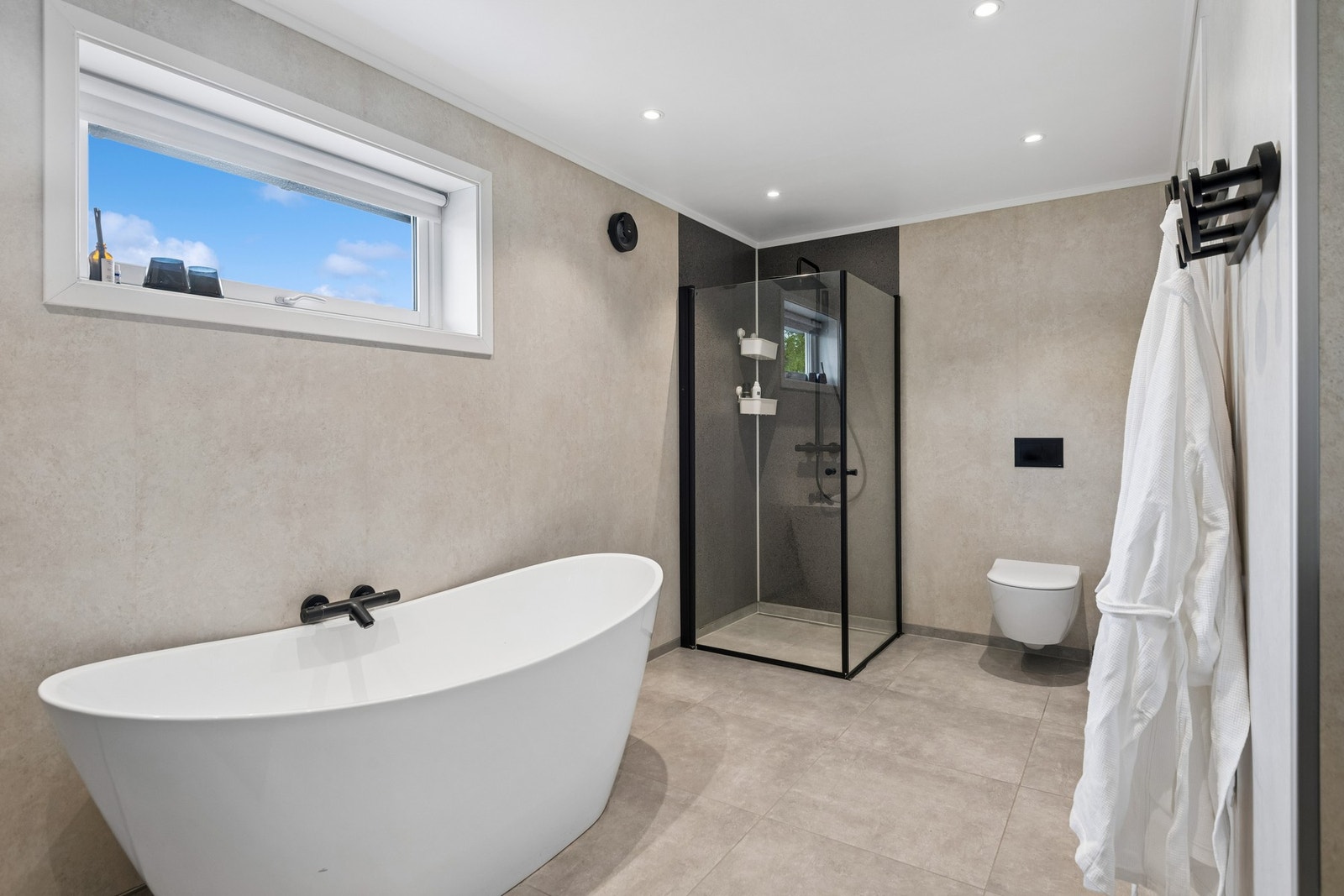 Badet har et dusjhjørne og vegghengt toalett. Galleribilde
