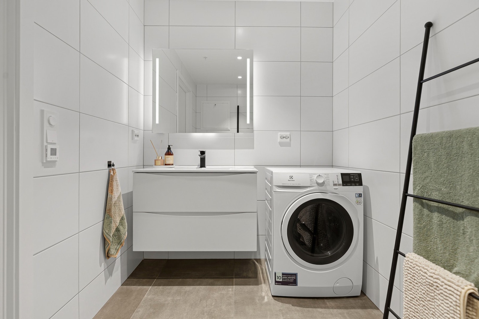 Badet fremstår lyst og moderne med flislagte overflater, stilren innredning og gjennomførte detaljer. Galleribilde