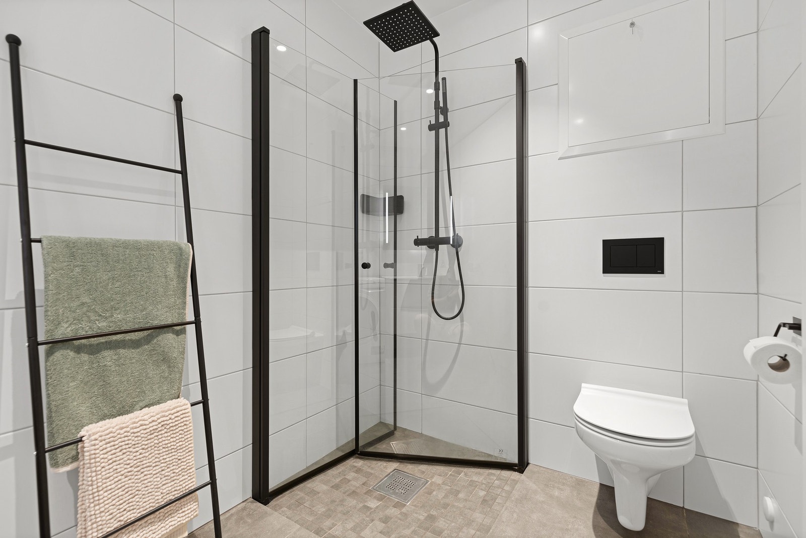 Badet er utført i moderne og tidsriktige materialer med store fliser på vegger, stilrene detaljer og en praktisk planløsning. Galleribilde
