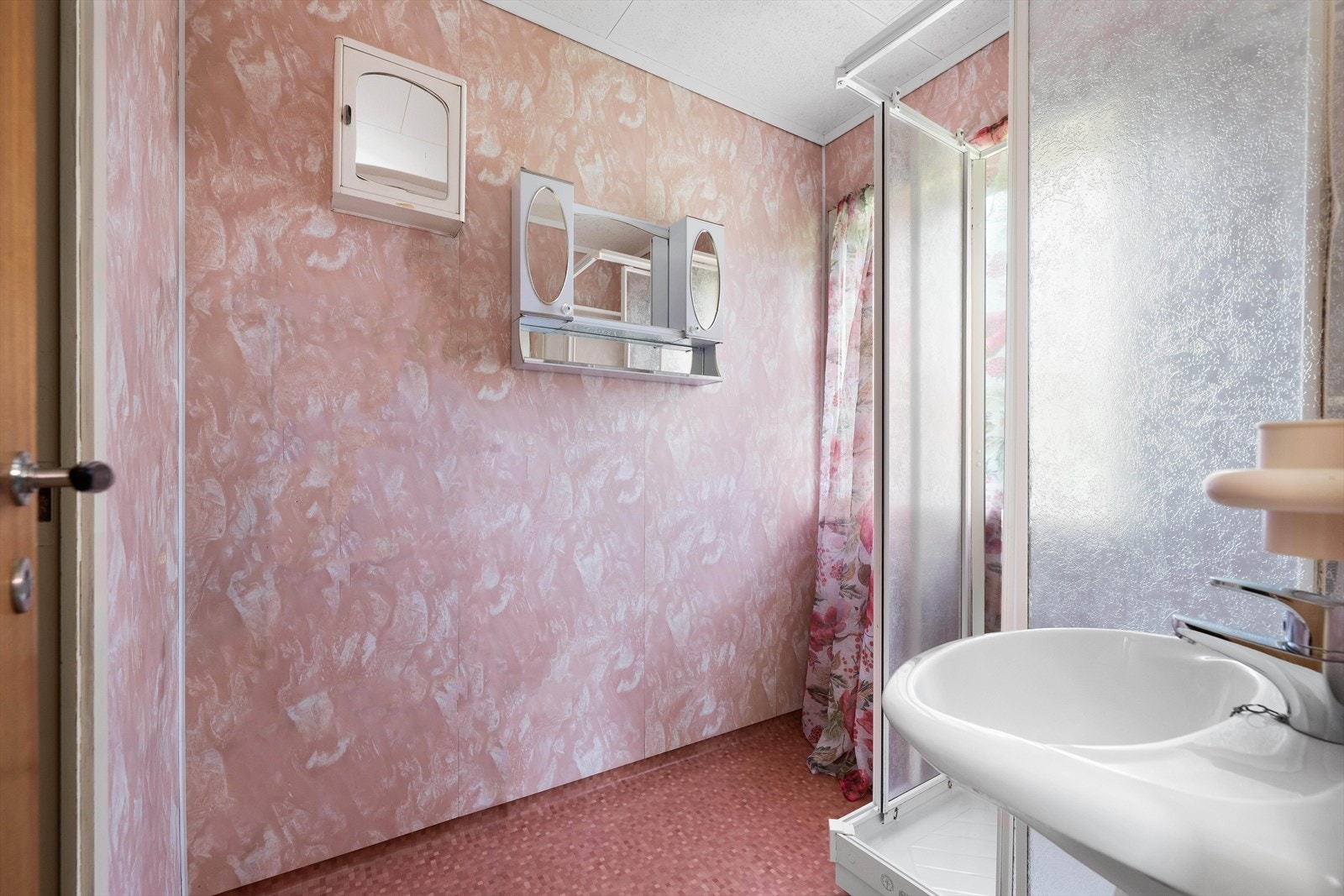 Badet er utstyrt med dusjkabinett og fritthengende vask. Noe oppbevaring i skap på vegg. Galleribilde