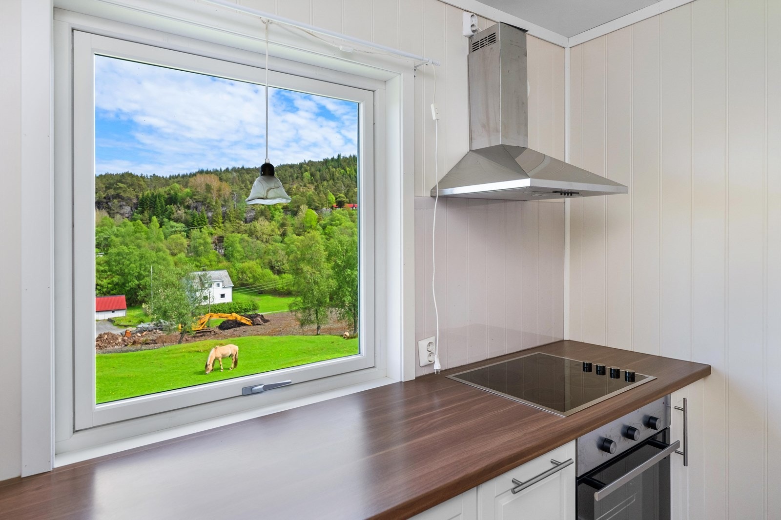 Hvitevarer er integrerte og medfølger. Over kokesonen henger en rustfri kjøkkenventilator med avtrekk ført ut av bygget. Galleribilde