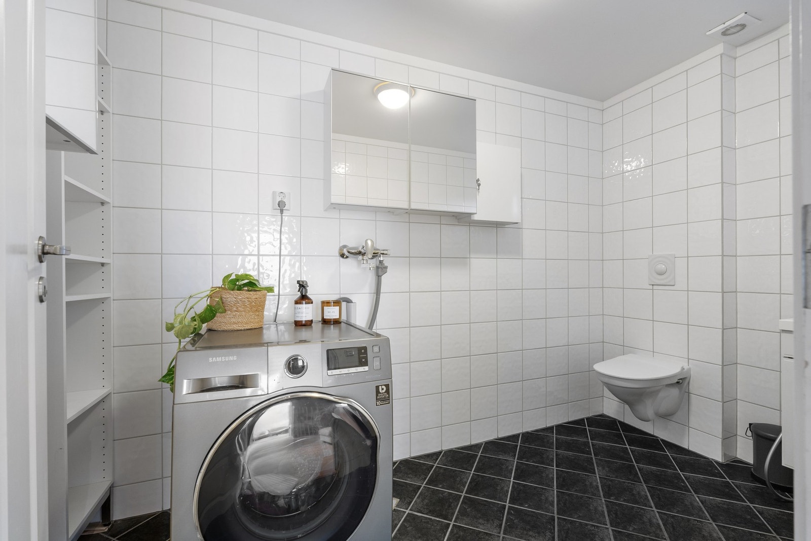 Separat vaskerom med opplegg til vaskemaskin og vegghent toalett med skjult sisterne. Galleribilde
