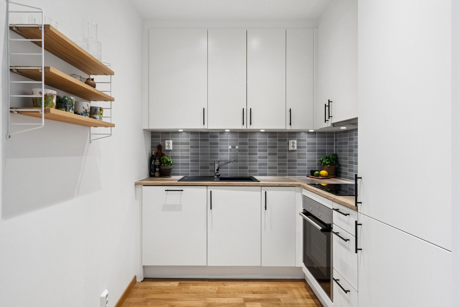 Kjøkkeninnredning med glatte, hvite fronter, laminat benkeplate og godt med skapplass. Galleribilde