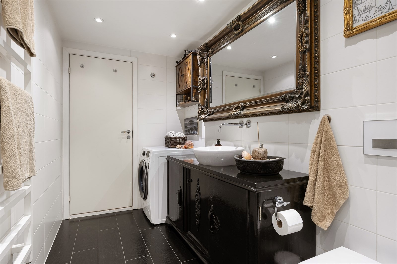 Badet har stor dusjnisje, servant med underskap, wc, speil, opplegg for vaskemaskin og elektrisk håndkletørker. Galleribilde