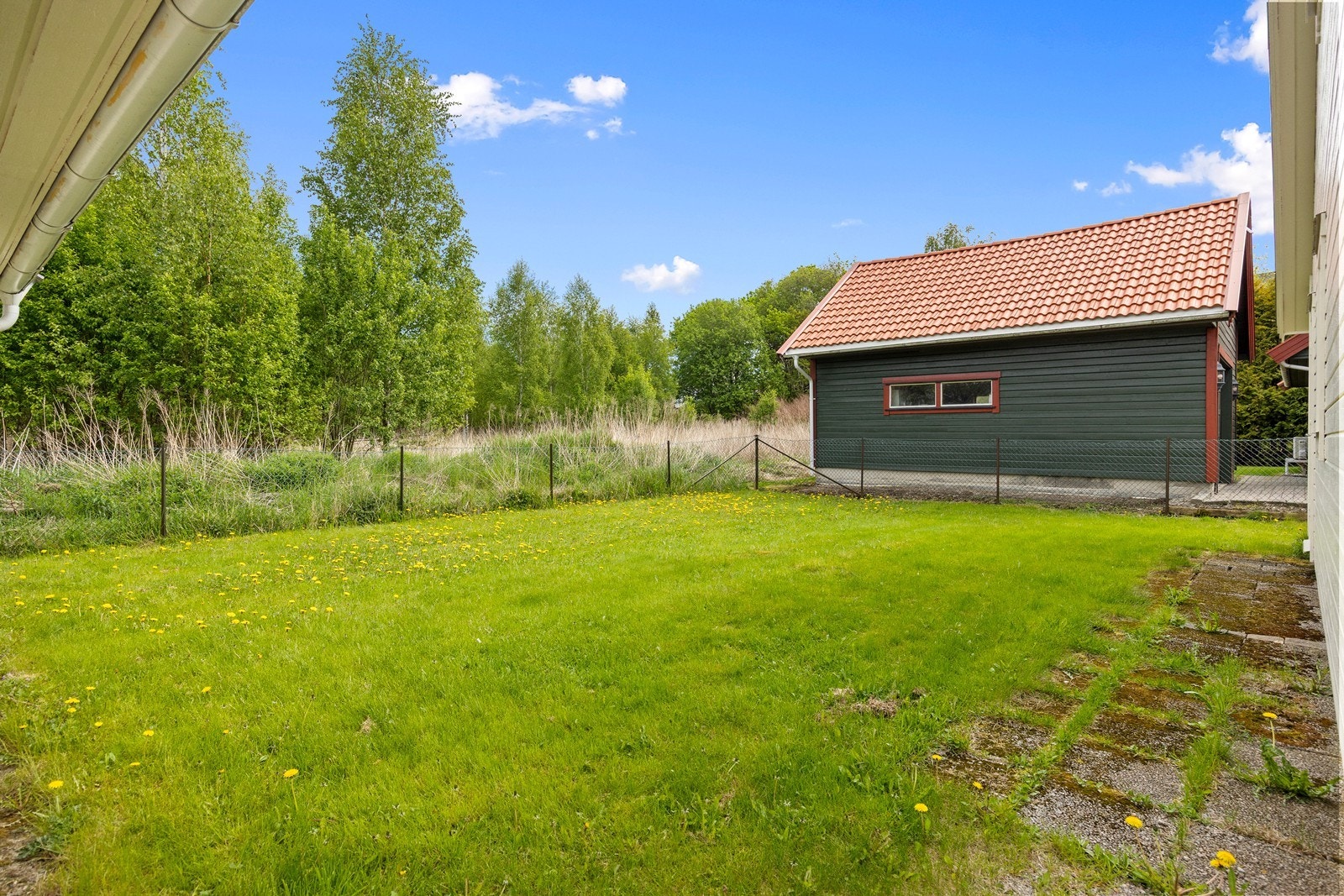 Tomten er flat og pent opparbeidet med gressplen, hekk og annen beplantning. Galleribilde