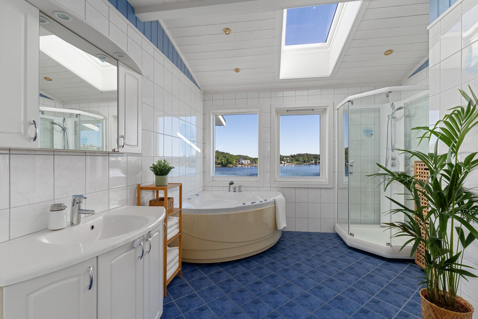Stort bad med badekar, dusjhjørne og lagring i servantskap og speilskap. Stilig detalj med lys fra takvindu. Galleribilde