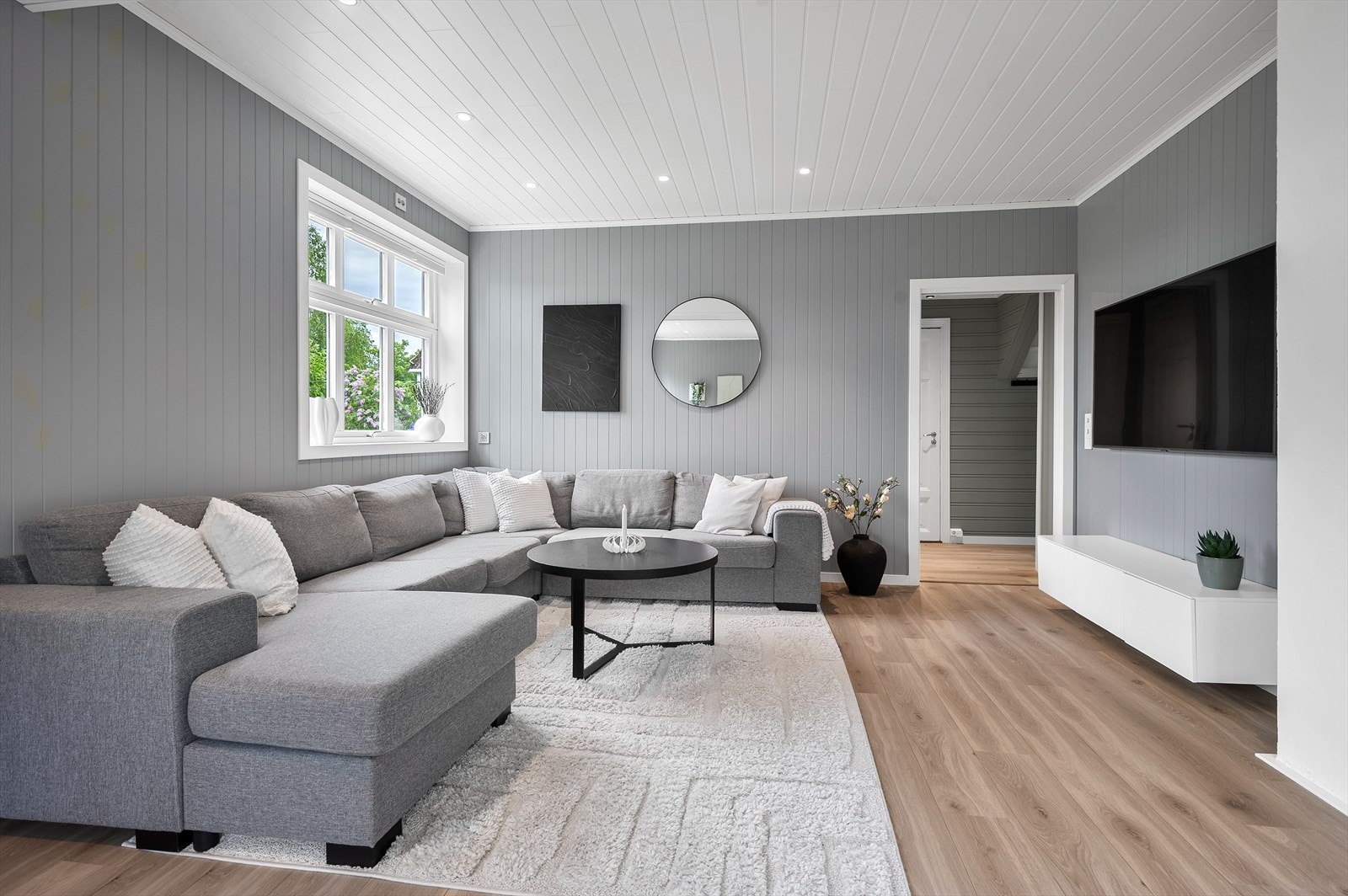 Stuen har vegger med malt trepanel og en åpen løsning som skaper en god romfølelse. Galleribilde