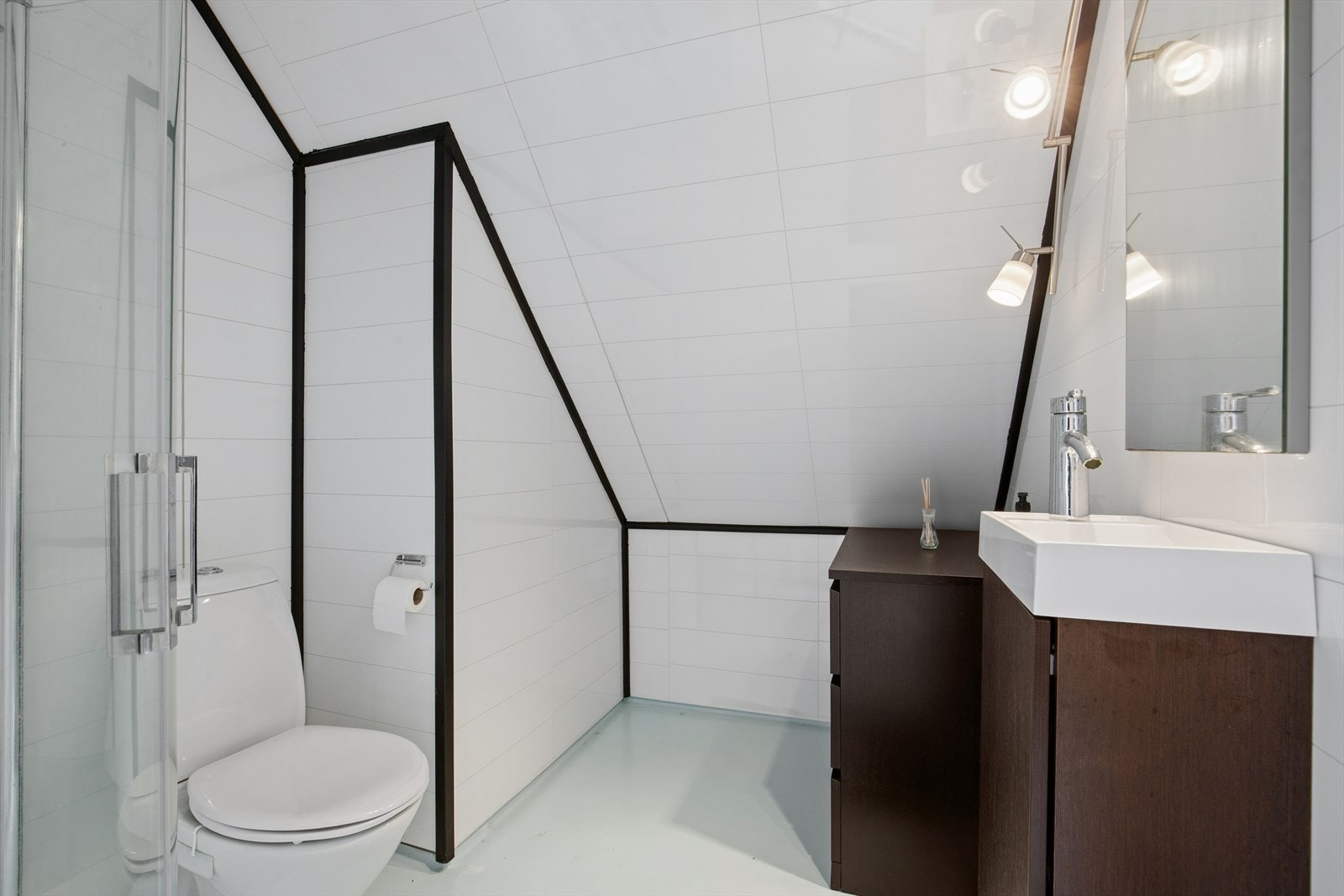 Badet i andre etasje har baderomsplater på veggene, vinylbelegg på gulv og dusjhjørne med glassdører. Galleribilde
