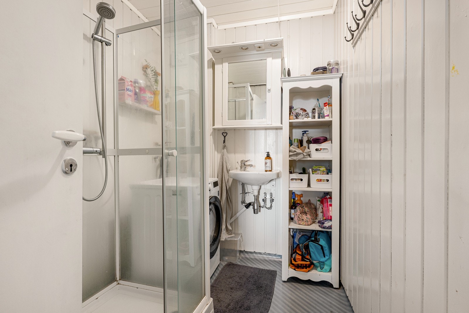 Badet er holdt i lyse fargetoner og har servant, speilskap, dusjkabinett og opplegg for vaskemaskin. Galleribilde