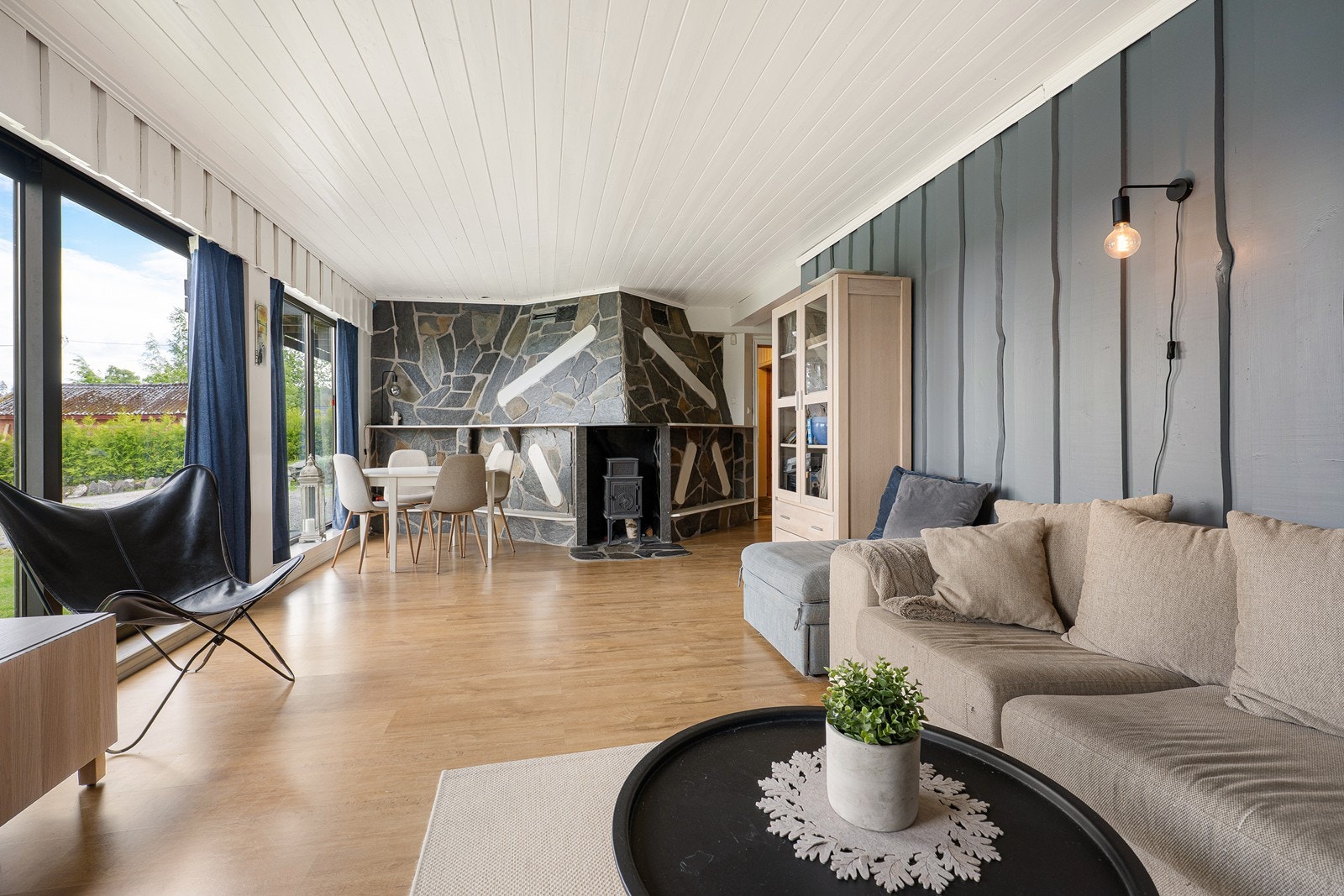 Store vindusflater sørger for rikelig med naturlig lysinnfall. Det er god plass til flere sittegrupper og en skiferkledd vegg gjør seg godt rundt en vedovn i støpejern. Galleribilde