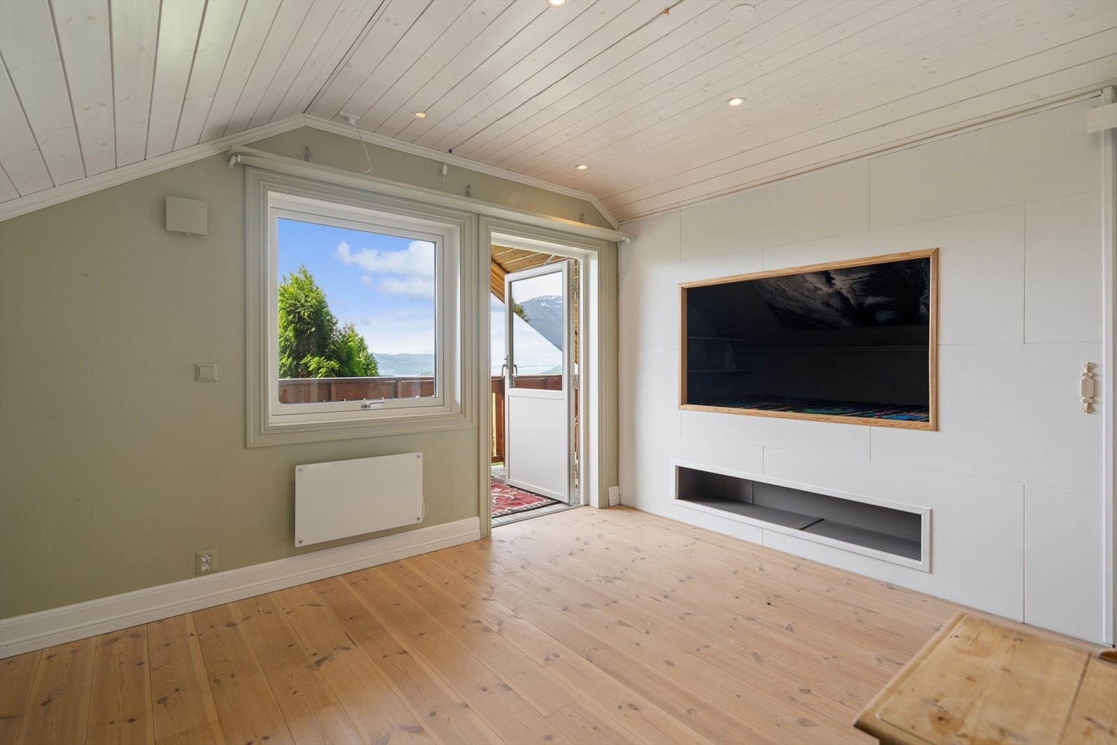 Rom i loftsetasjen med plassbygd TV-benk og utgang til verandaen. Galleribilde