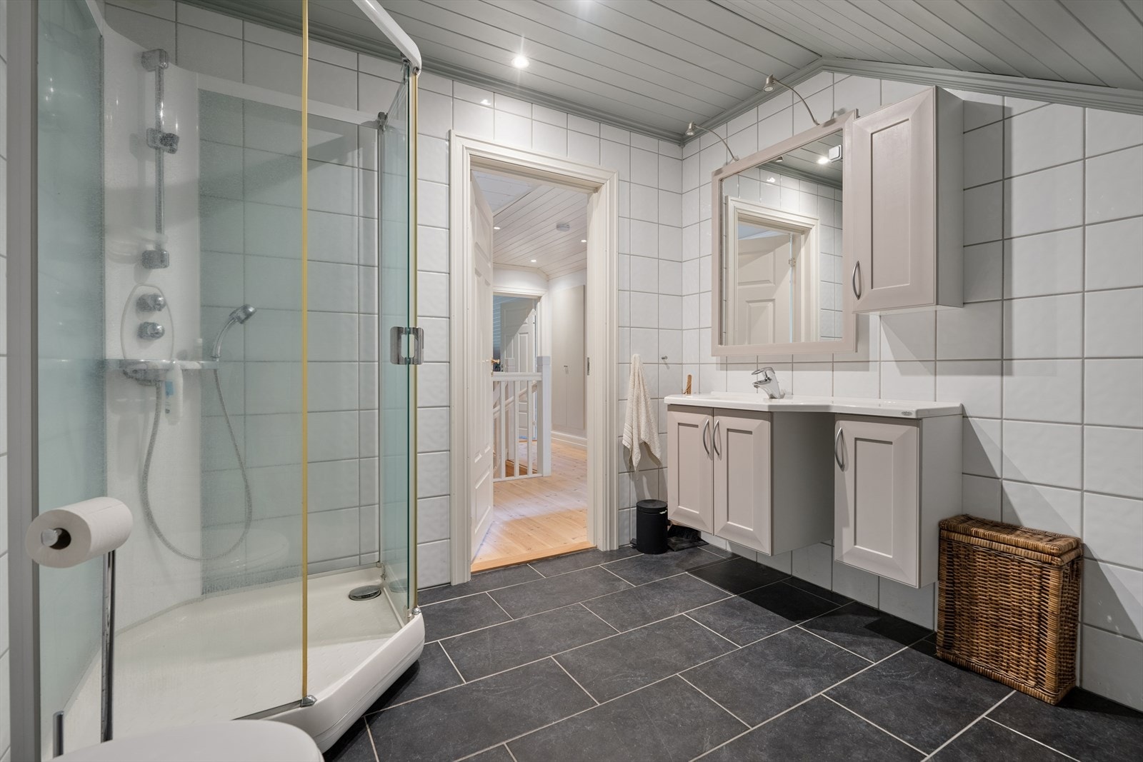 Badet i loftsetasjen har flislagt gulv med varmekabler og et praktisk dusjkabinett. Galleribilde