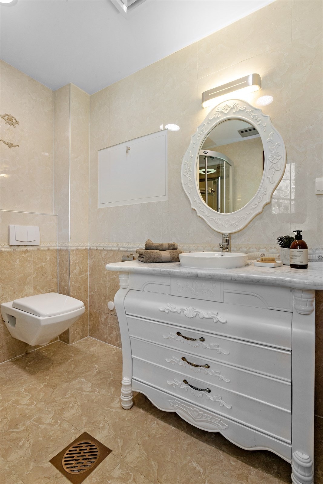 Badet er innredet med veggmontert toalett med innebygget sisterne og servantskap. Galleribilde