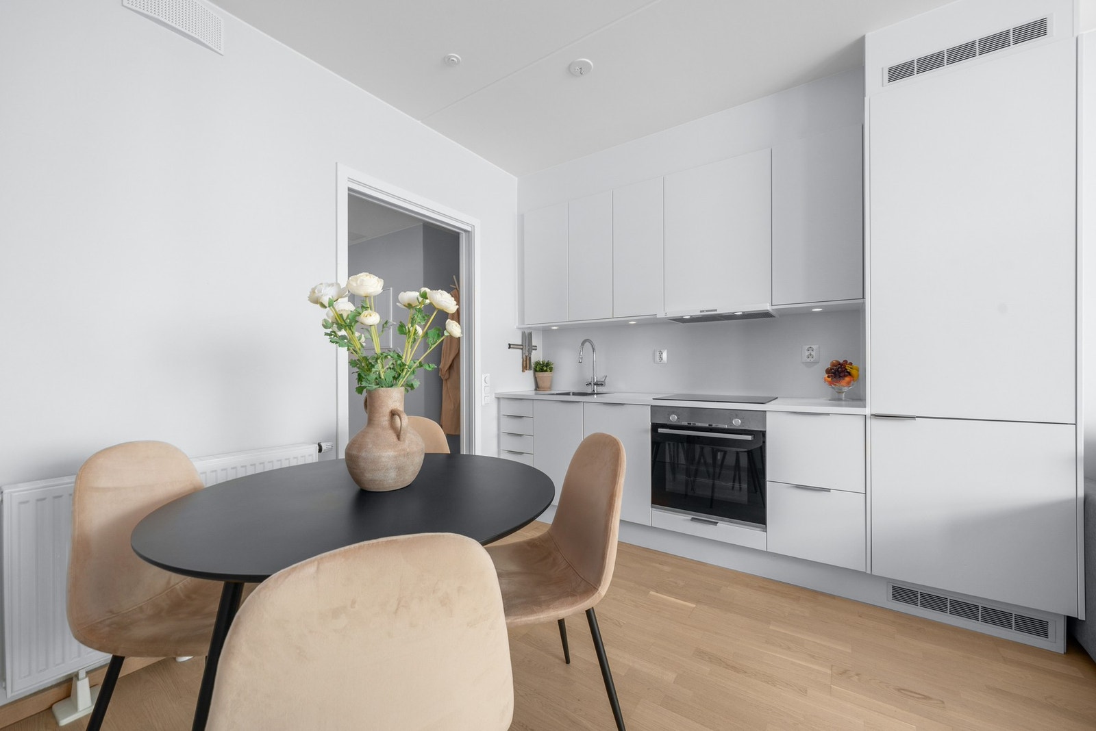 Den åpne kjøkkenløsningen gir en naturlig plass til spisebord i forkant, og skaper en hyggelig overgang mellom matlaging, måltider og sofasonen. Galleribilde
