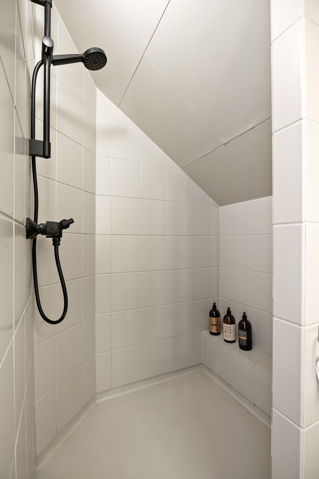Badet er utstyrt med gulvstående toalett (2025) og dusjnisje med veggmontert dusjarmatur. Galleribilde