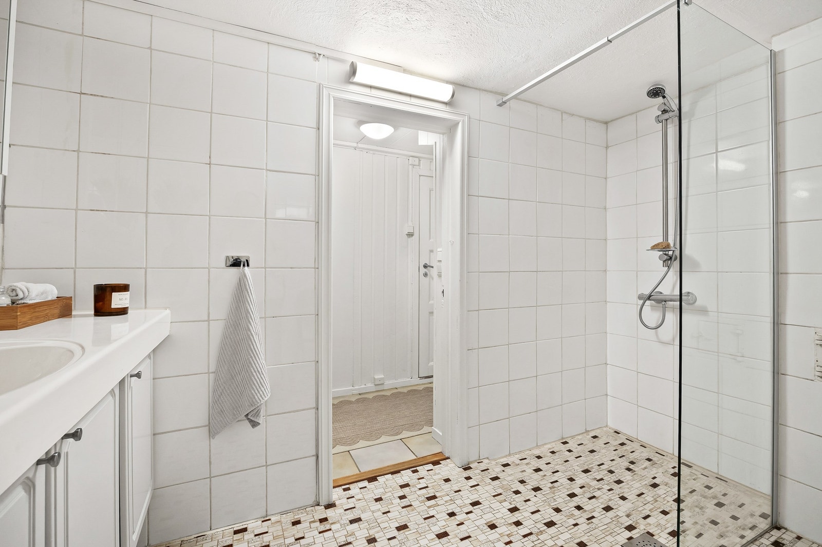 Dusj i hjørne med veggmontert dusjarmatur og dusjvegg av glass (dusjvegg fra 2023). Galleribilde