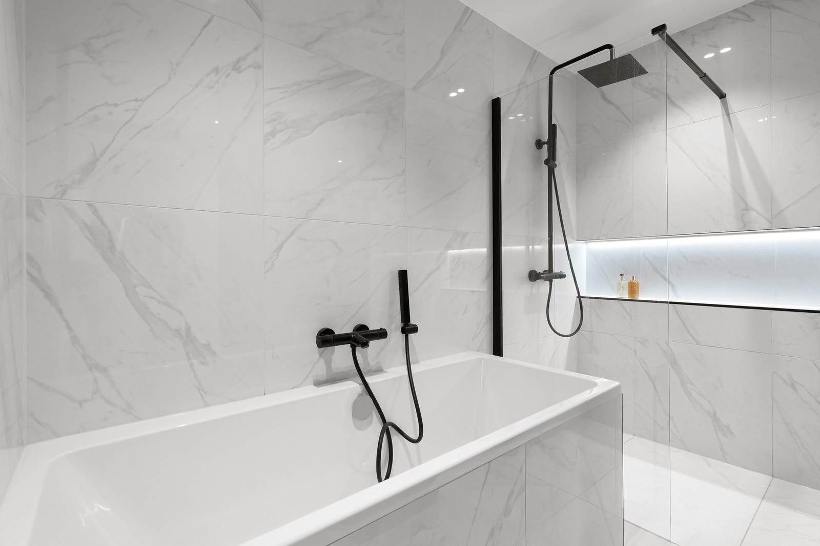 Badet er videre utstyrt med vegghengt toalett, innmurt badekar og en romslig dusjsone med både regnfallsdusj og hånddusj. Galleribilde