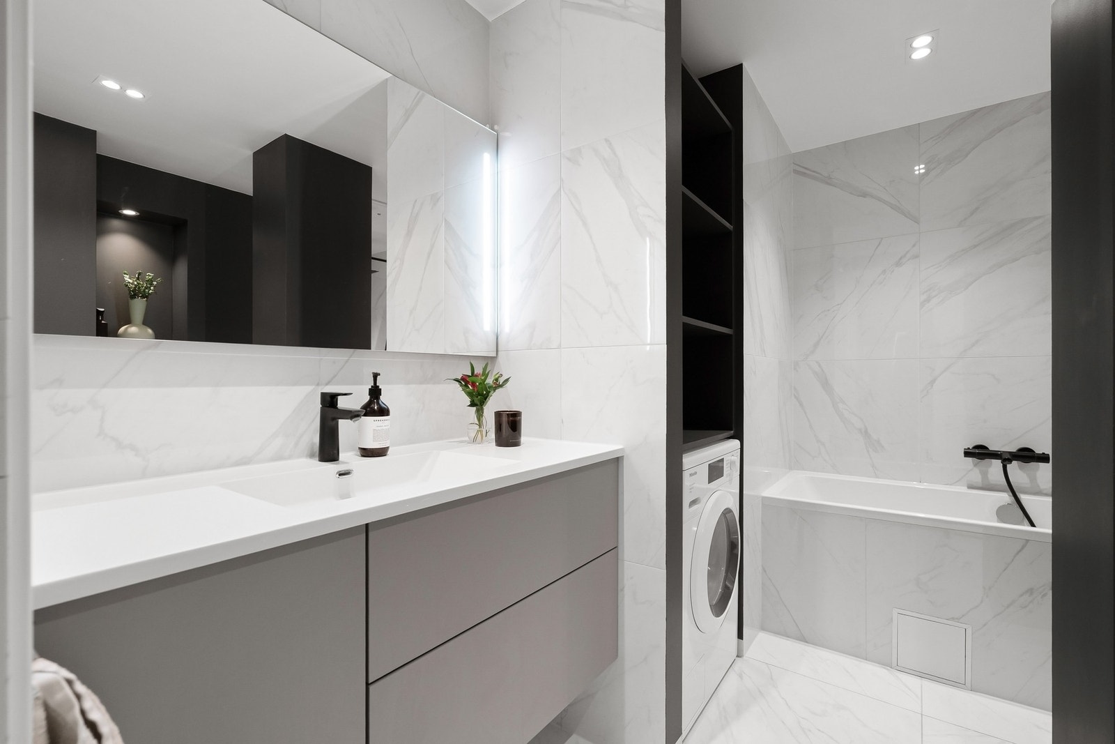 Badet har store marmorfliser på gulv og vegger, kombinert med malte veggflater som gir en fin kontrast. Galleribilde