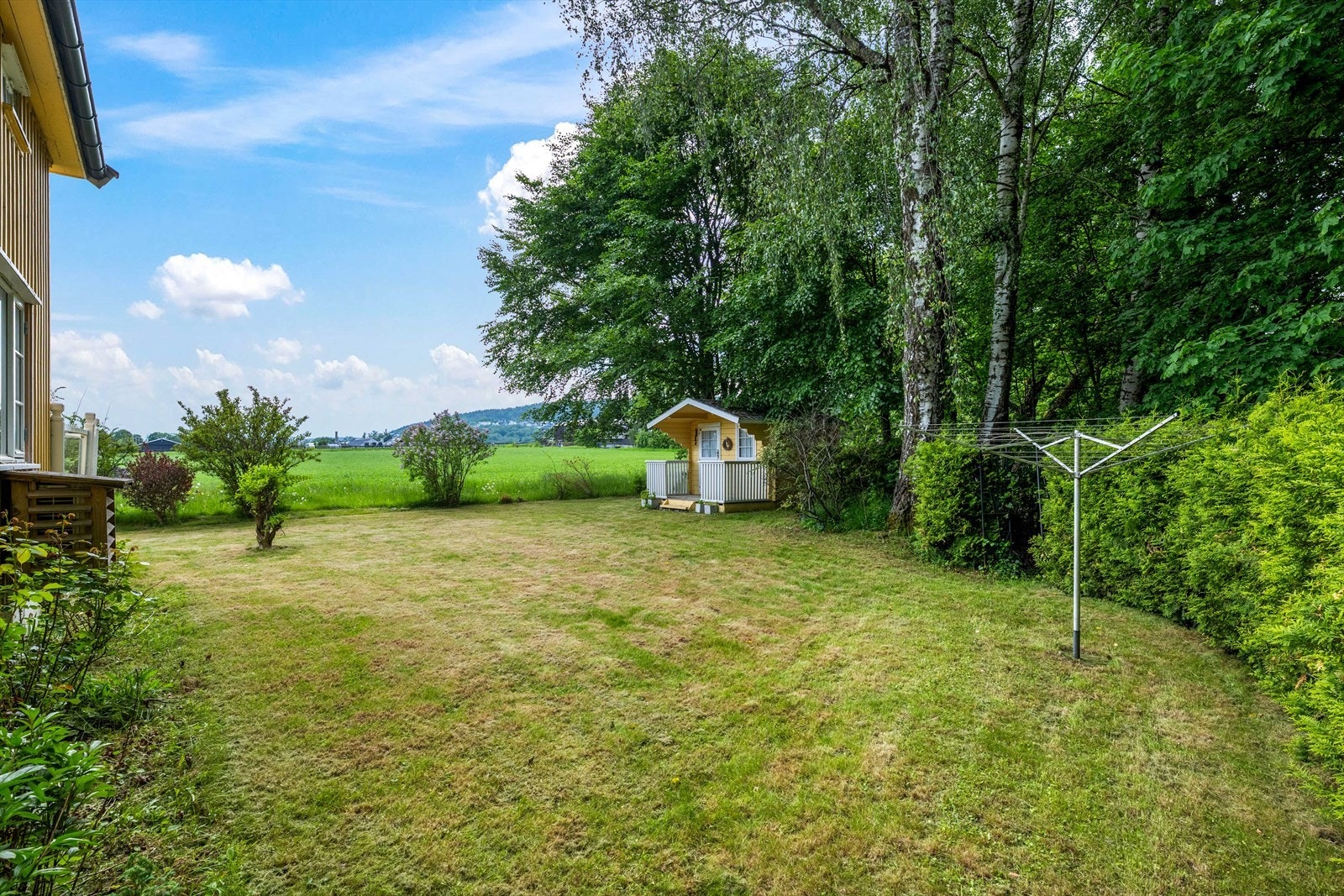 Eiendommen har en relativt flat tomt med plen og beplantning. Galleribilde