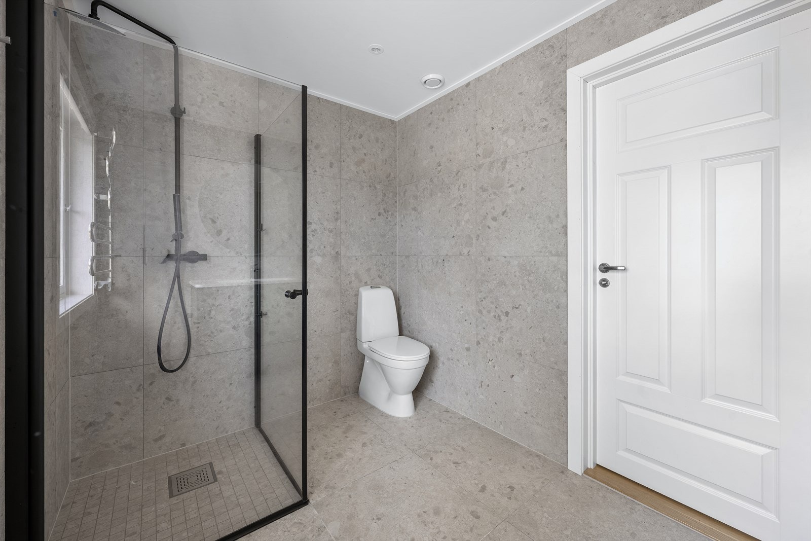 Videre er badet utstyrt med regnfallsdusj med innfellbare glassdører og downlightsbelysning i tak Galleribilde
