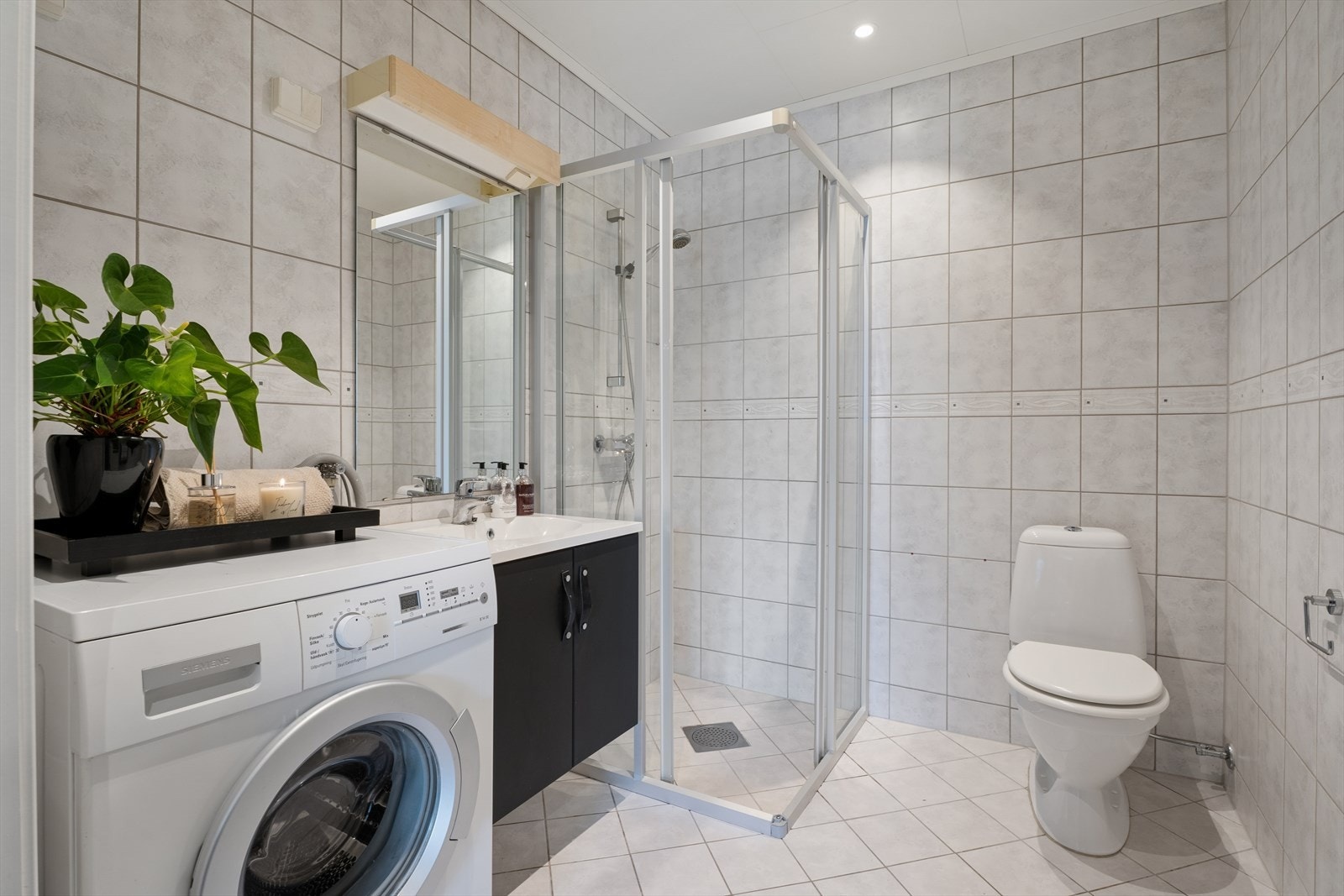 Badet har flislagte vegger og gulv, og er utstyrt med servant med underskap, toalett og dusjløsning med vegger/hjørne. Det er tilrettelagt for vaskemaskin, og gulvet har elektriske varmekabler som sørger for god komfort. Galleribilde