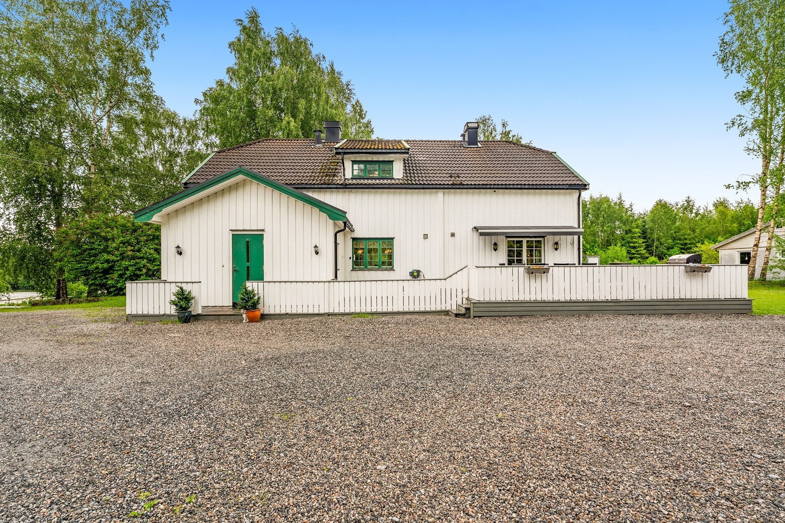 Eneboligens fasade med stående, hvitmalt kledning. Galleribilde