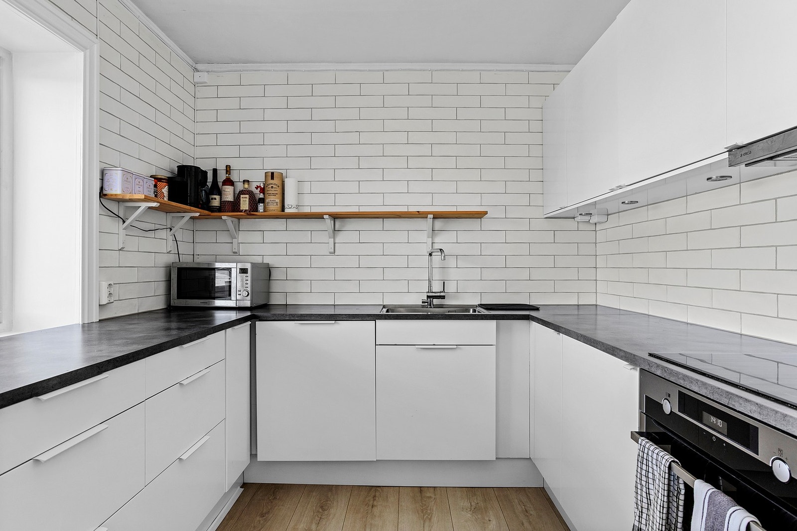 Kjøkkenet har innredning med glatte fronter og benkeplate av laminat, med integrert kjøl/fryseskap, oppvaskmaskin, induksjonstopp, stekeovn og komfyrvakt. Gulv av laminat, flislagte vegger med malte plater og malt tak Galleribilde