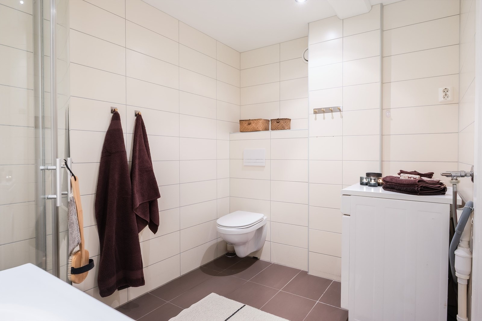 Badet har veggmontert toalett og opplegg for vaskemaskin. Galleribilde