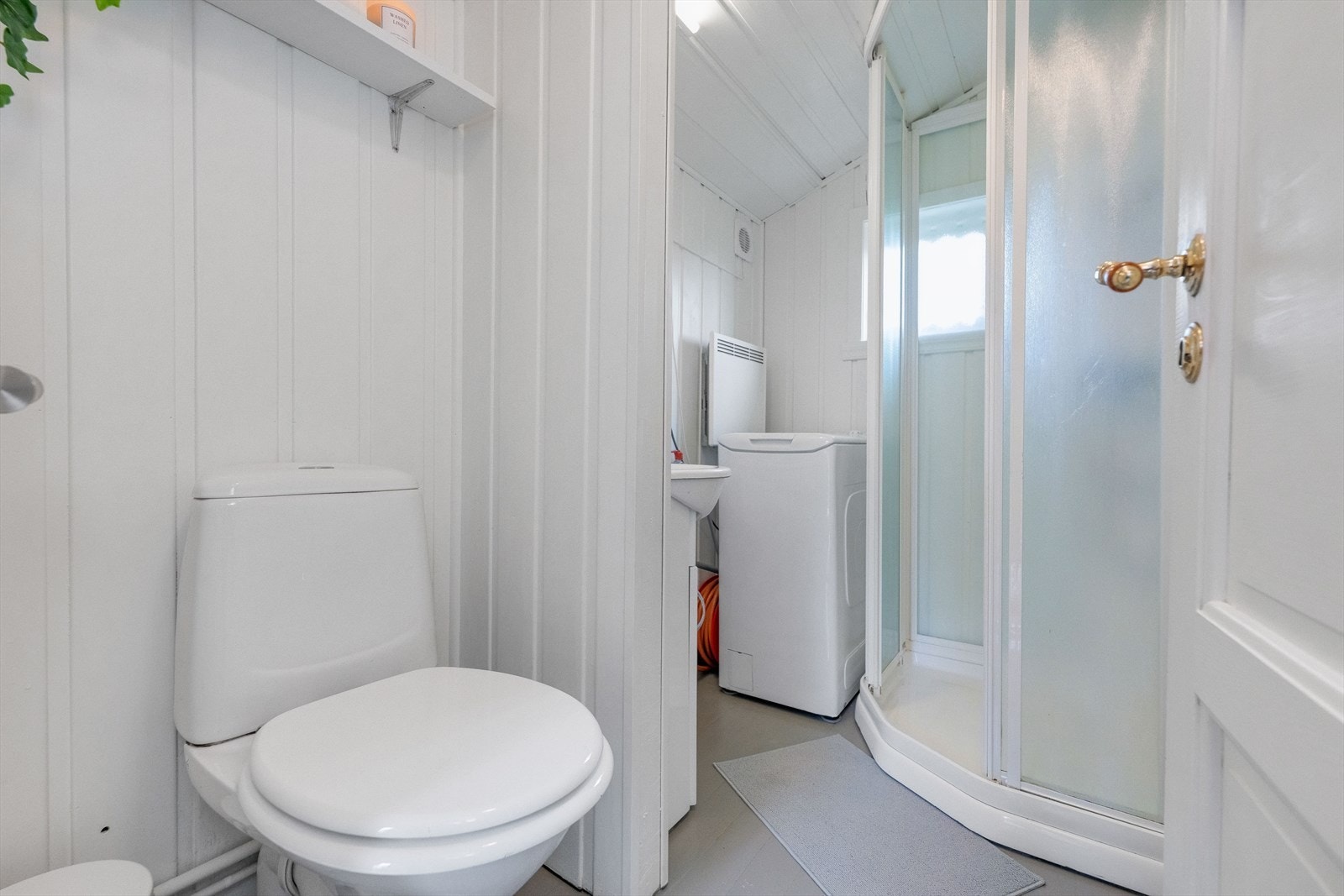 Badet ligger rett ved og er innredet med dusjkabinett, servant og gulvstående toalett samt opplegg til vaskemaskin. Galleribilde