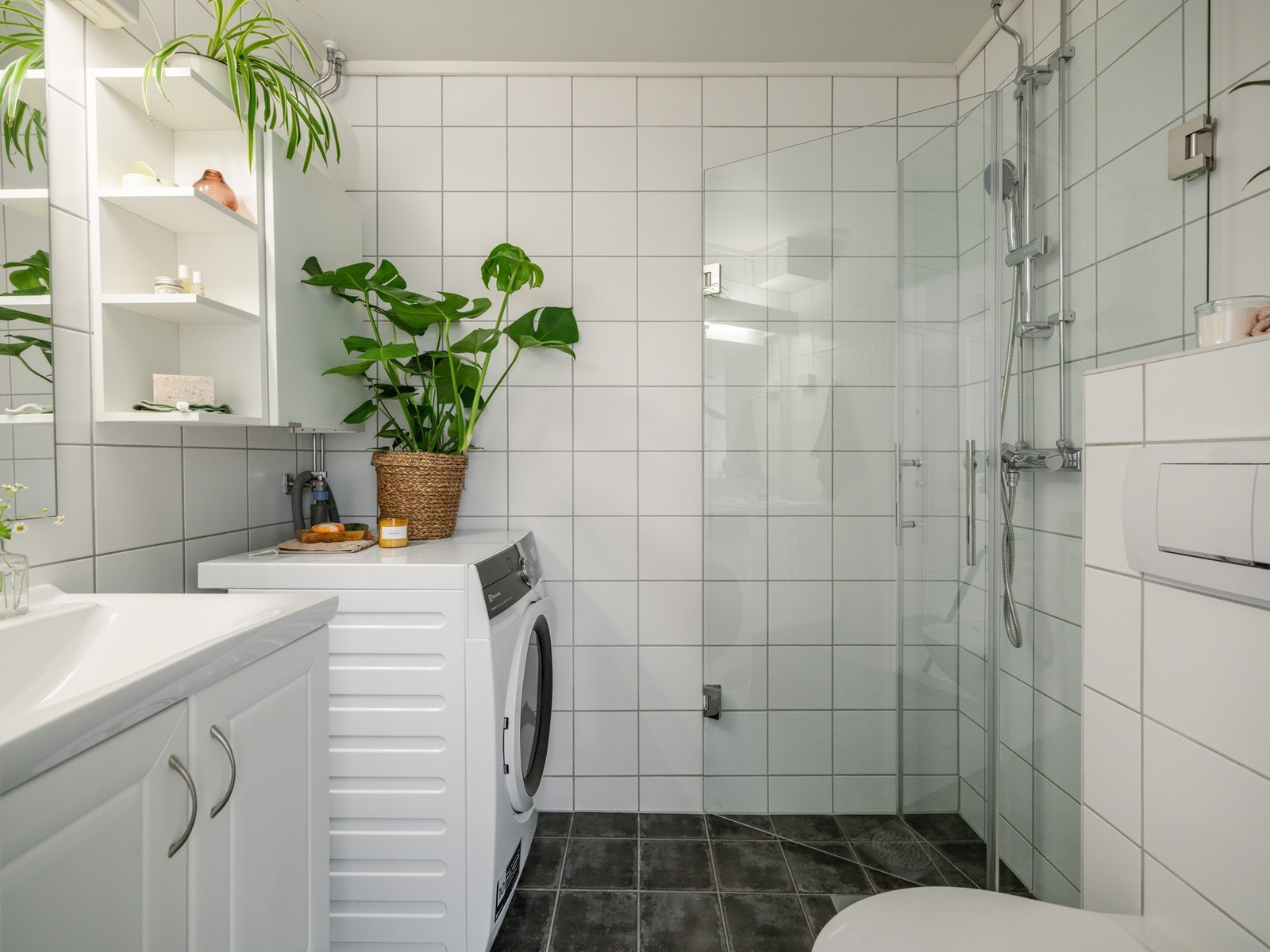 Badet er pent flislagt og innredningen består av servant med underskap, vegghengt toalett, dusjhjørne med innfellbare dører og vegghengt skap. Galleribilde