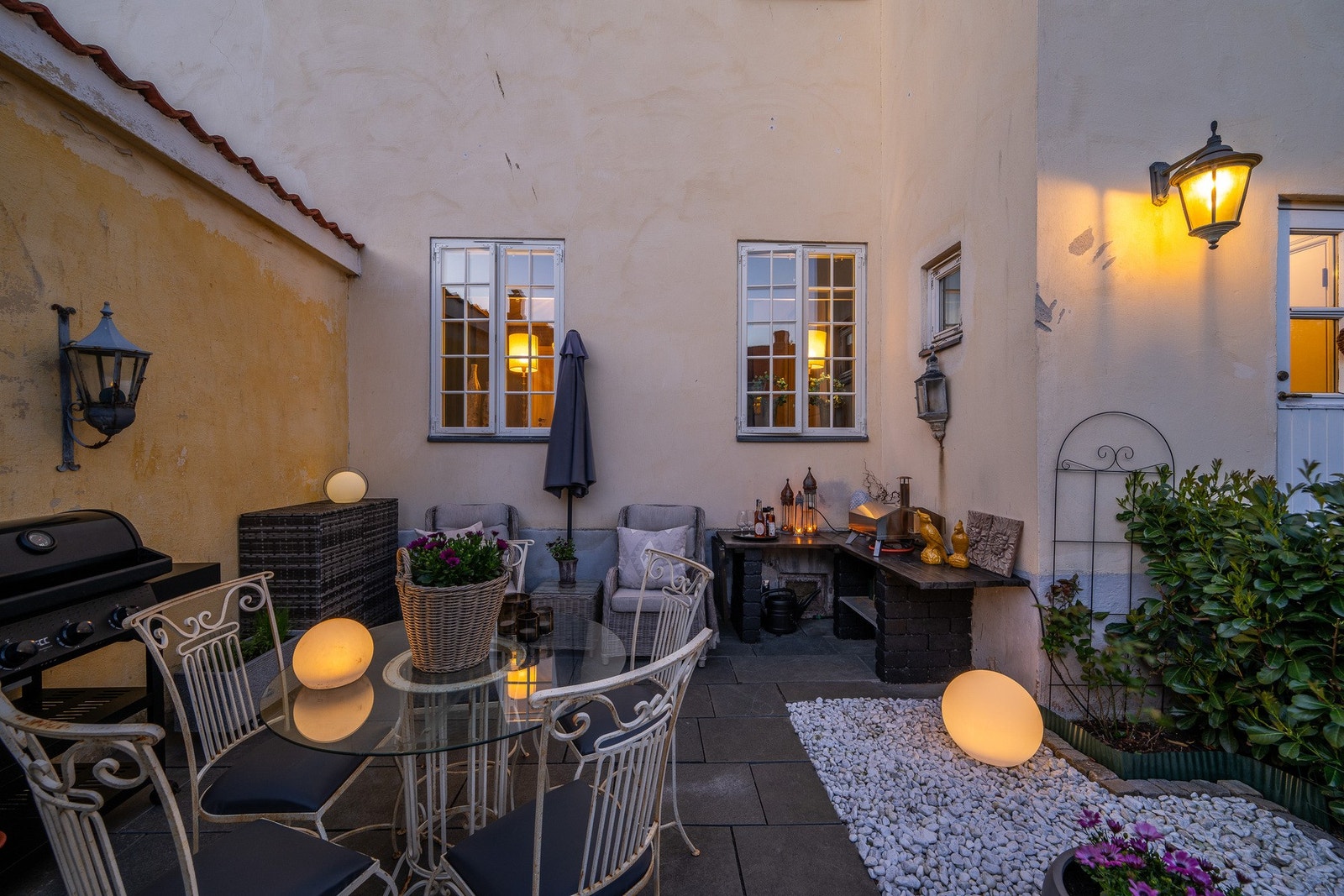 Uteplassen er hellelagt, pent beplantet slik at man sitter skjermet for innsyn og laget til en praktisk plass til pizzaovnen Galleribilde