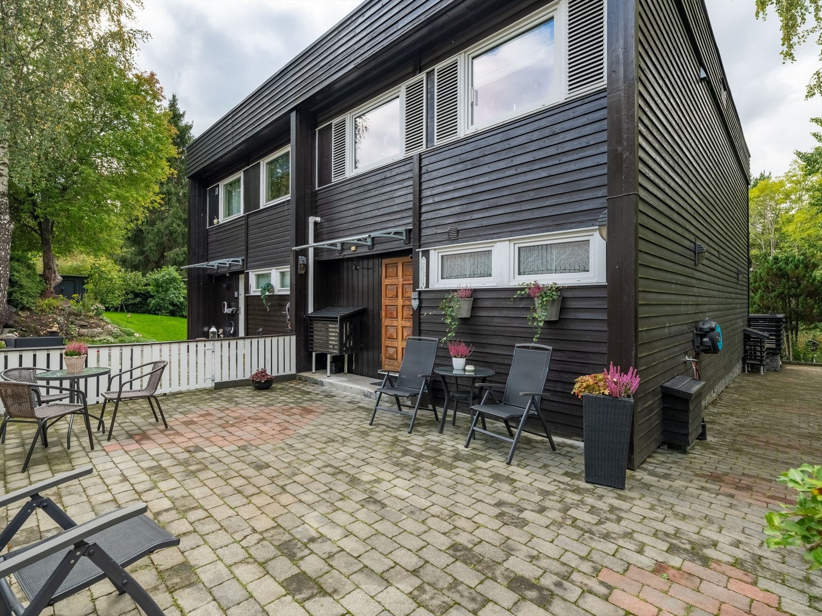 Plassen ved inngangspartiet er steinbelagt og gir et helhetlig og innbydende uttrykk. Galleribilde