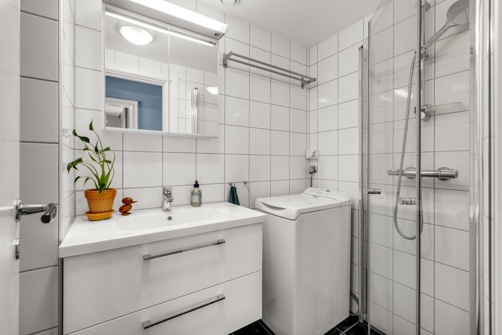 Pent, flislagt bad med varmekabler i gulvet. Badet er innredet med vegghengt servantinnredning med ovenpåliggende vask og speilskap med belysning over vasken. Galleribilde