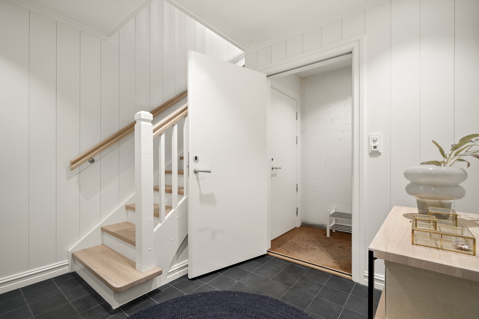 Fra entreen fører den malte trappen med eiketrinn opp til boligens øvrige etasjer. Galleribilde