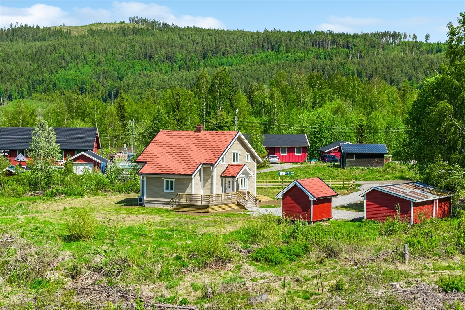 Eneboligen ligger på en slakt skrånende tomt med gruset adkomst, naturtomt og gressarealer. Galleribilde