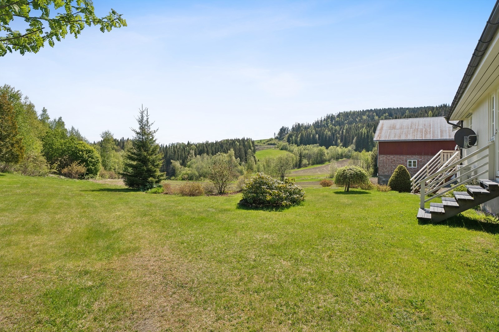 Eiendommen har en stor og åpen hage med plen og beplantning. Galleribilde