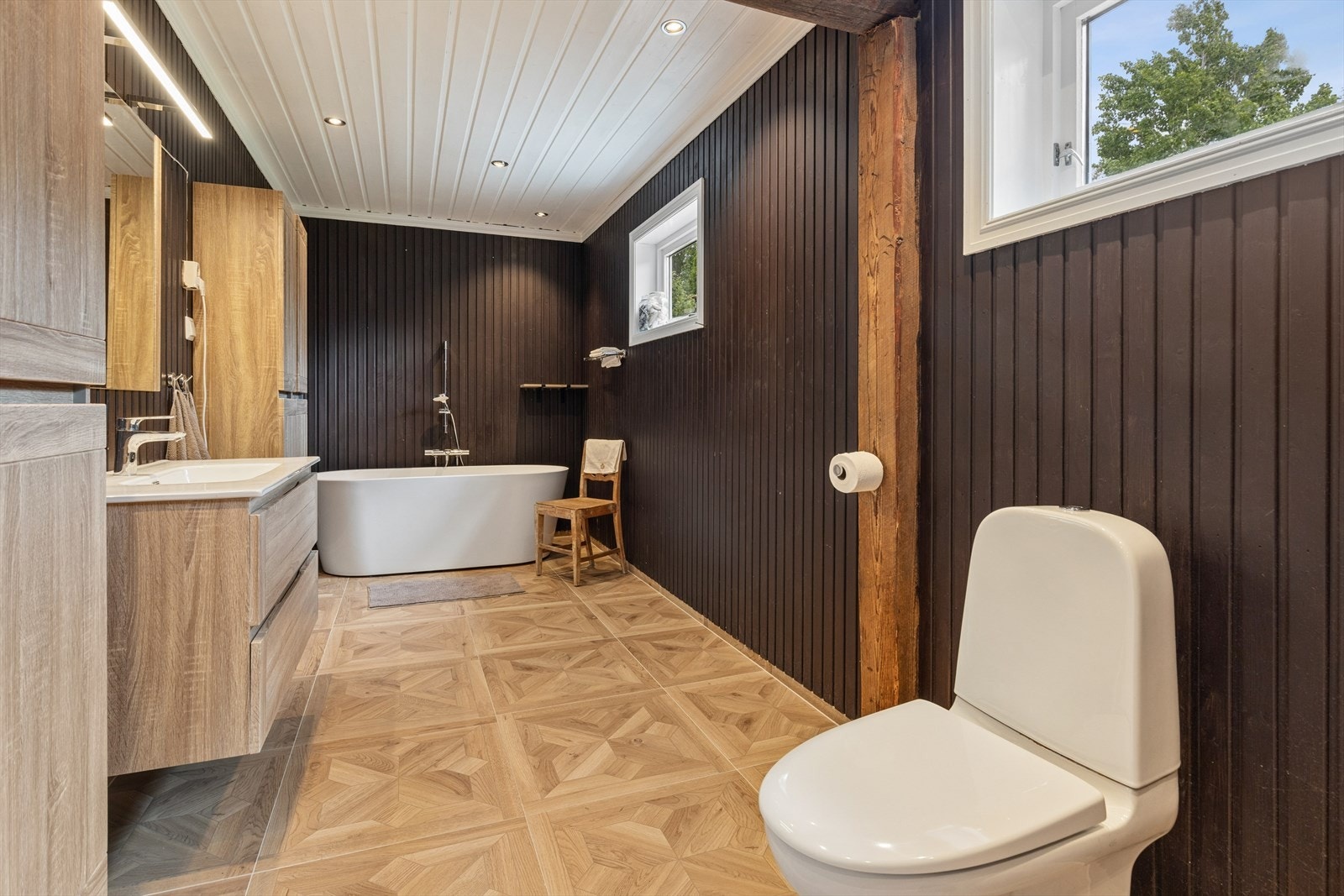 Badet i første etasje har badekar, flislagt gulv med varmekabler og panel på veggene. Galleribilde
