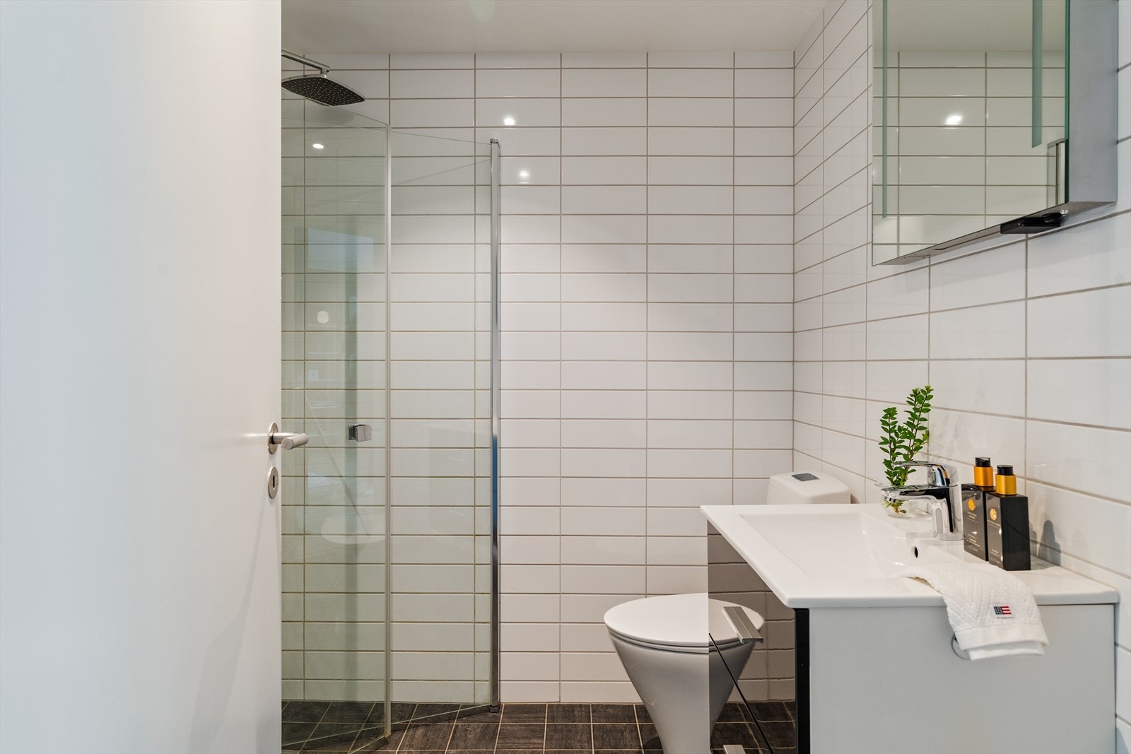 Badet fremstår moderne, delikat og funksjonelt med helflisede overflater som gir et eksklusivt uttrykk. Galleribilde