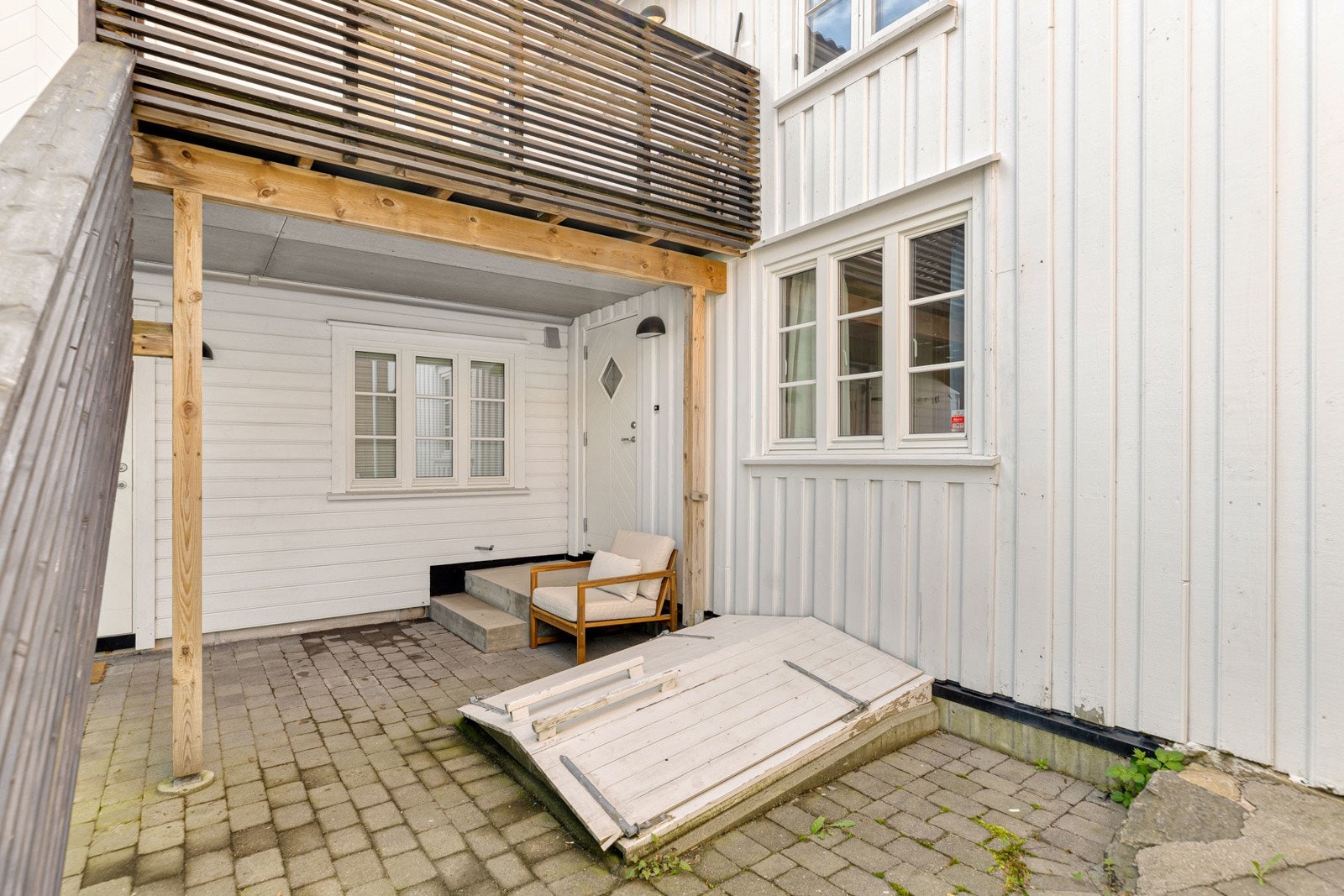 Lettstelt bakgård med belegningstein - inngang til leiligheten og trapp ned til romslig bod Galleribilde
