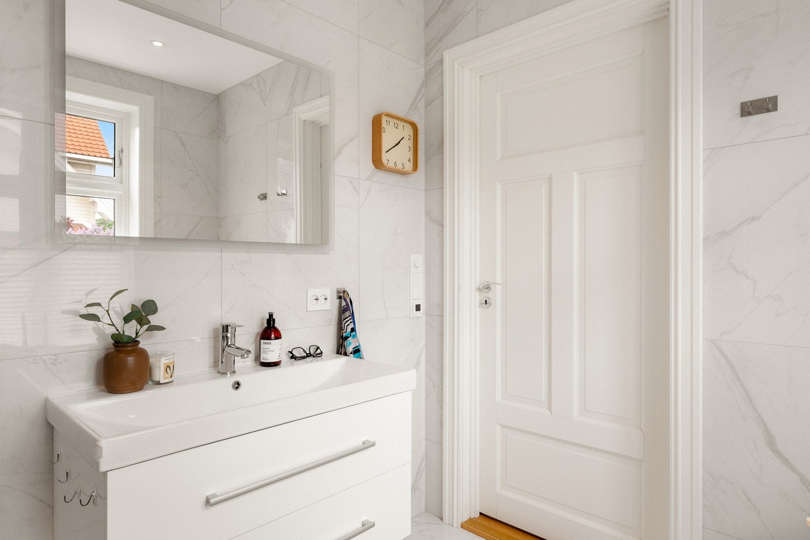 Hovedbadet er fra 2022/23 og har et lyst og elegant uttrykk. Store, hvite fliser med marmormønster dekker både vegger og gulv og gir rommet en eksklusiv karakter Galleribilde