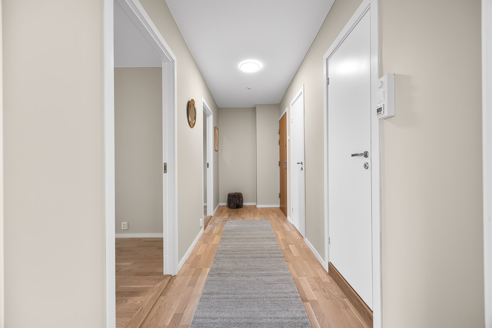 Lys og innbydende entré med malte, slette veggflater og nytt eikeparkettgulv fra 2026. Her er det god plass til oppbevaring av yttertøy og sko. Galleribilde