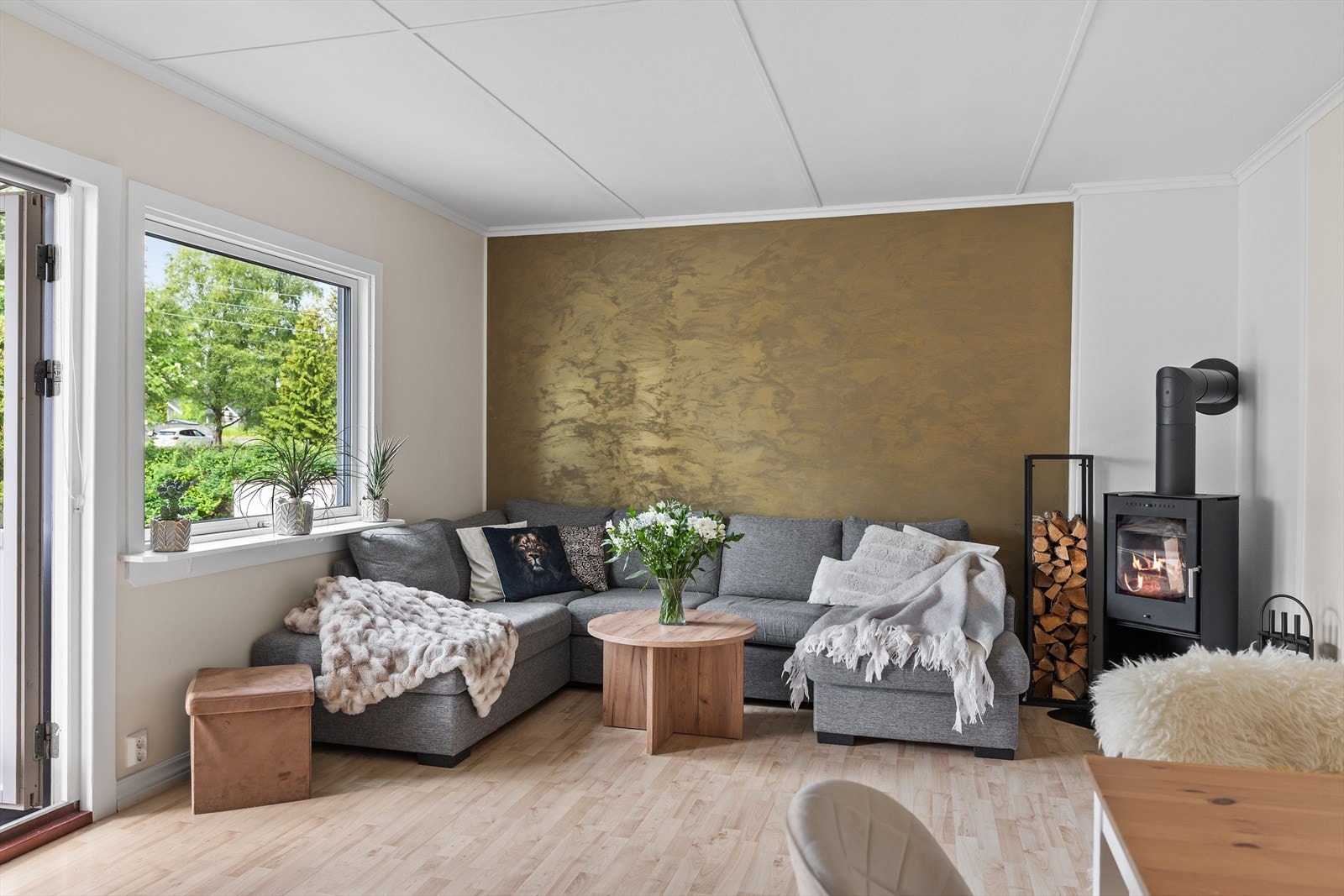Stuen fremstår som lys, innbydende og trivelig, med store vindusflater som slipper inn godt med naturlig lys og skaper en luftig atmosfære. En flott dekorvegg tilfører rommet karakter og gir et moderne og stilfullt uttrykk. Galleribilde