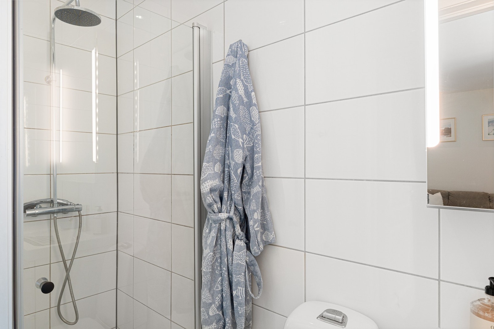 Baderommet inneholder dusjnisje, gulvmontert WC, kran og avløp for vaskemaskin, underskap, veggskap og speilskap. Galleribilde
